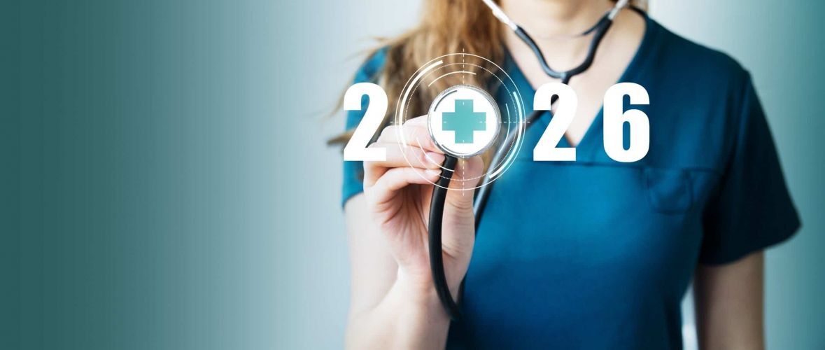 Symbolfoto Pflege 2026: Pflegekraft hält Stethoskop mit digitalem Kreuz-Icon und Jahreszahl 2026 im Hintergrund.