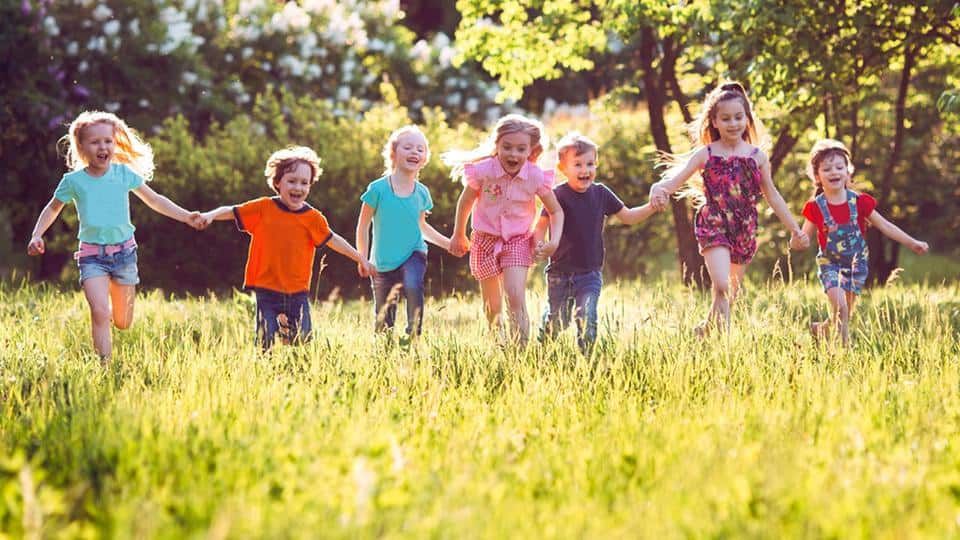 Kinder spielen gemeinsam fröhlich im Grünen – Symbolbild für die Förderung von Kindern aus sozial benachteiligten Familien