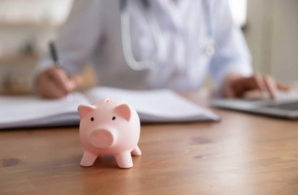 Sparschwein auf einem Tisch mit Pfleger im Hintergrund – Symbolbild für Pflegegeld und professionelle Pflegedienste