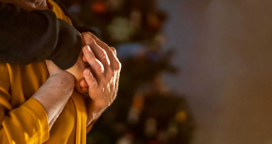 Nahaufnahme von zwei Händen, die sich an Weihnachten liebevoll halten; symbolisiert Nähe, Unterstützung und häusliche Betreuung.