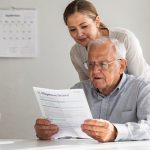 Senior liest Pflegegrad-Bescheid, Tochter schaut mit