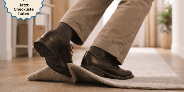 Ein Fuß, der über eine Teppichfalte stolpert - symbolbild für die Sturzgefahr Zuhause